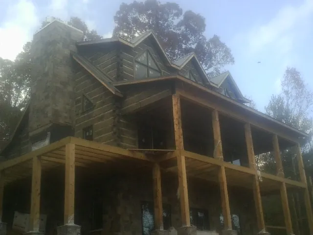 Stone chimney and dormers on a large log home with a timber porch in Lexington